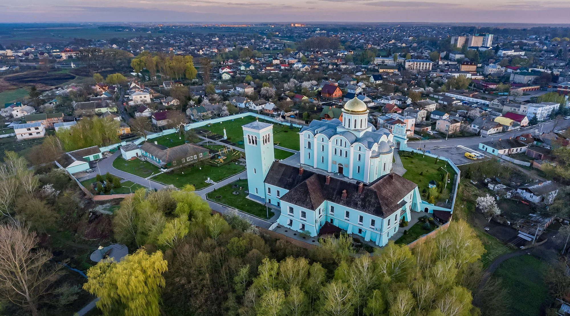 Аерофото блакитного собору із золотою банею серед міста на заході сонця