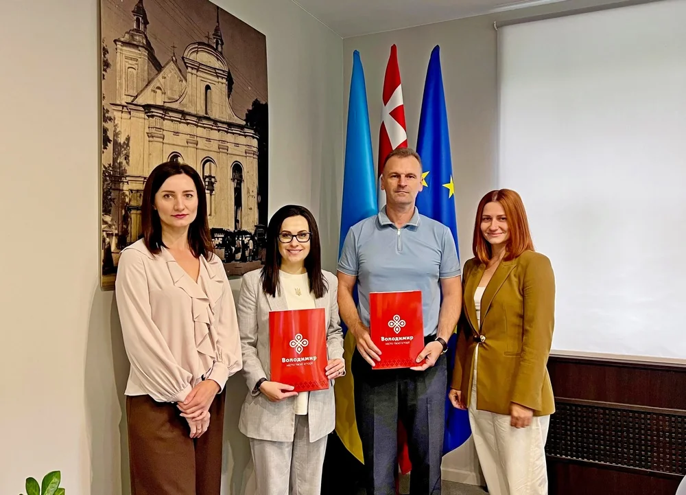 Чотири люди з папками Володимир біля прапорів України, Данії та ЄС