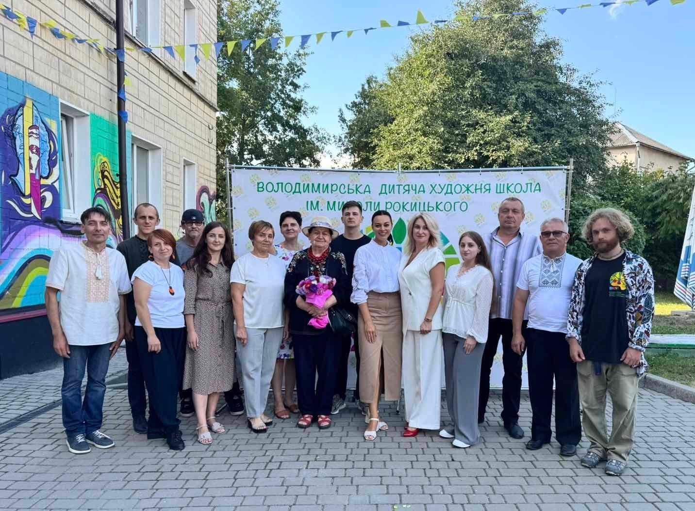 Групове фото людей біля банера Володимирської дитячої художньої школи